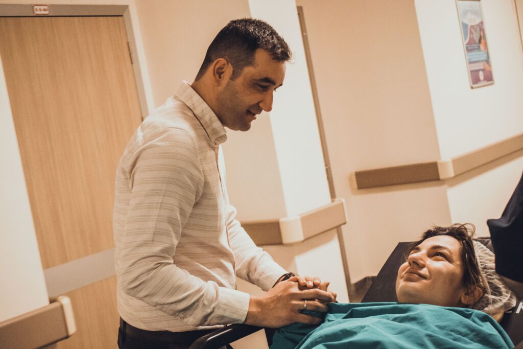 A man comforts a patient in a hospital corridor, symbolizing care and support.