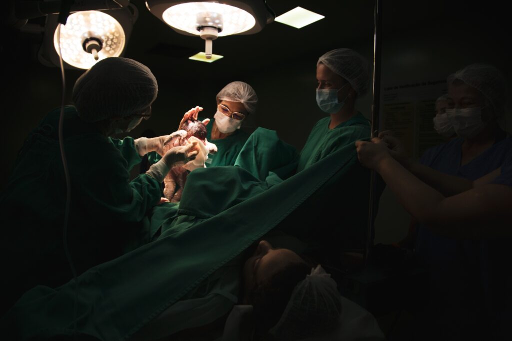 Doctors and nurses delivering a newborn baby under surgical lights in a hospital.