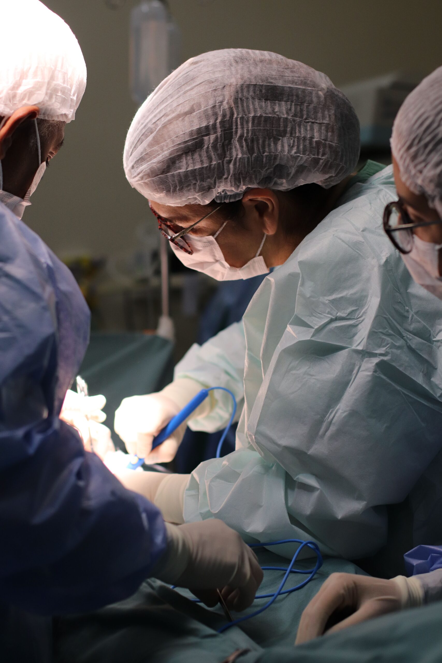 Focused team of surgeons in surgical gear operating under clinical lighting in a hospital.