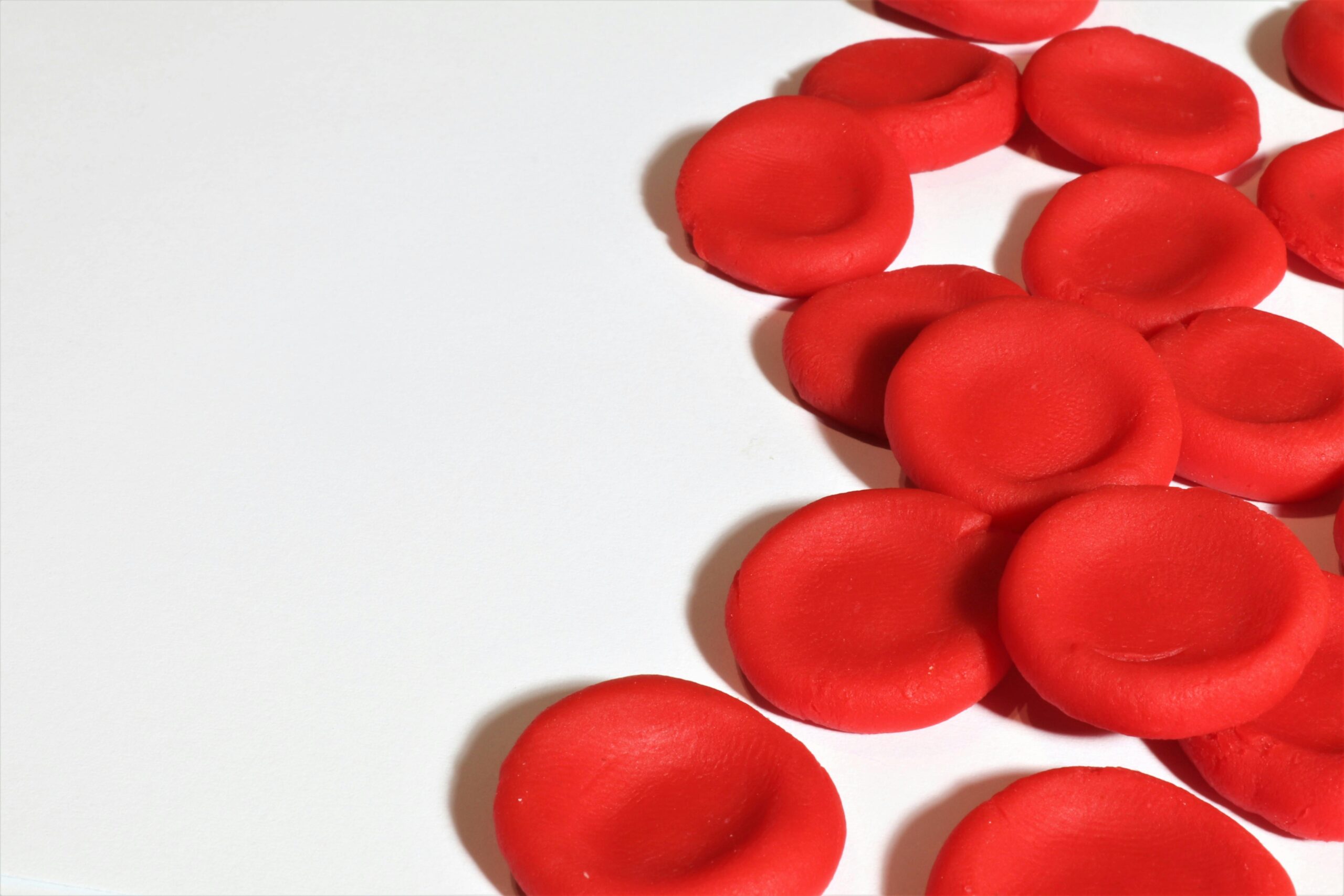 Artistic depiction of red blood cells on a white background, emphasizing medical concepts.