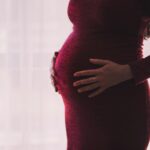 Silhouette of a pregnant woman gently holding her belly, emphasizing motherhood and anticipation.