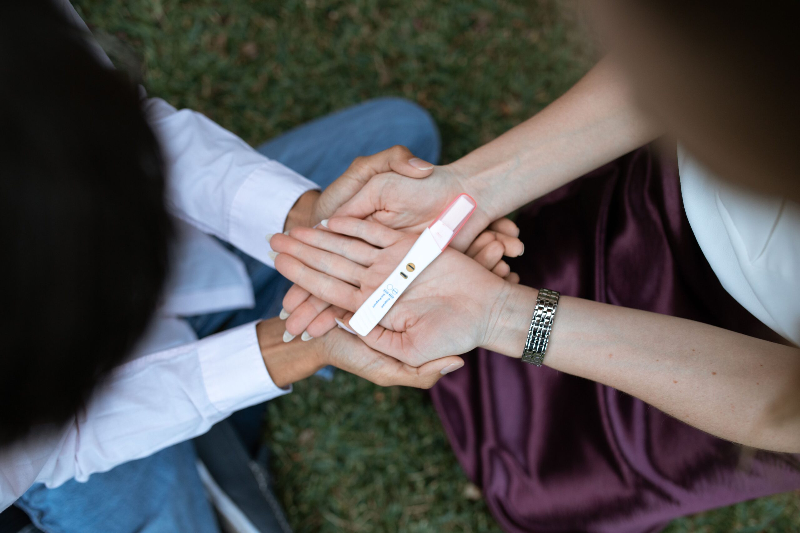 A couple shares a positive pregnancy test result outdoors, symbolizing anticipation and joy.