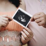 Close-up of a couple sharing an ultrasound photo, symbolizing pregnancy and family joy.