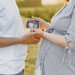 A couple holds an ultrasound image, representing pregnancy and family love, in an outdoor setting.