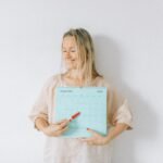 Smiling woman points at a date on a calendar, conveying excitement and anticipation.