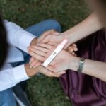A couple shares a positive pregnancy test result outdoors, symbolizing anticipation and joy.