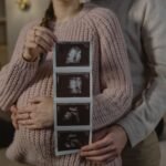 Expectant couple indoors holding ultrasound, symbolizing new life and family bonds.