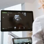 Healthcare professional viewing ultrasound scan on a monitor during a medical examination.