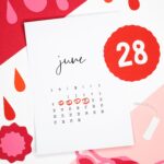 Flat lay of a June calendar with menstrual cycle dates highlighted, surrounded by period symbols.
