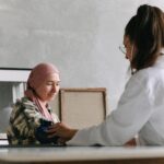 Doctor checks blood pressure of a patient wearing a headscarf indoors, focused on healthcare.