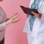 Close-up of a patient consulting a doctor with a clipboard in a medical setting.