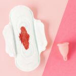 A sanitary pad and menstrual cup on a pink background, highlighting menstrual hygiene.