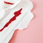 Close-up of stained menstrual pads on a pink surface highlighting women's health and menstruation.