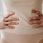 Close-up of a woman's hands resting on her waist, showcasing nude clothing.